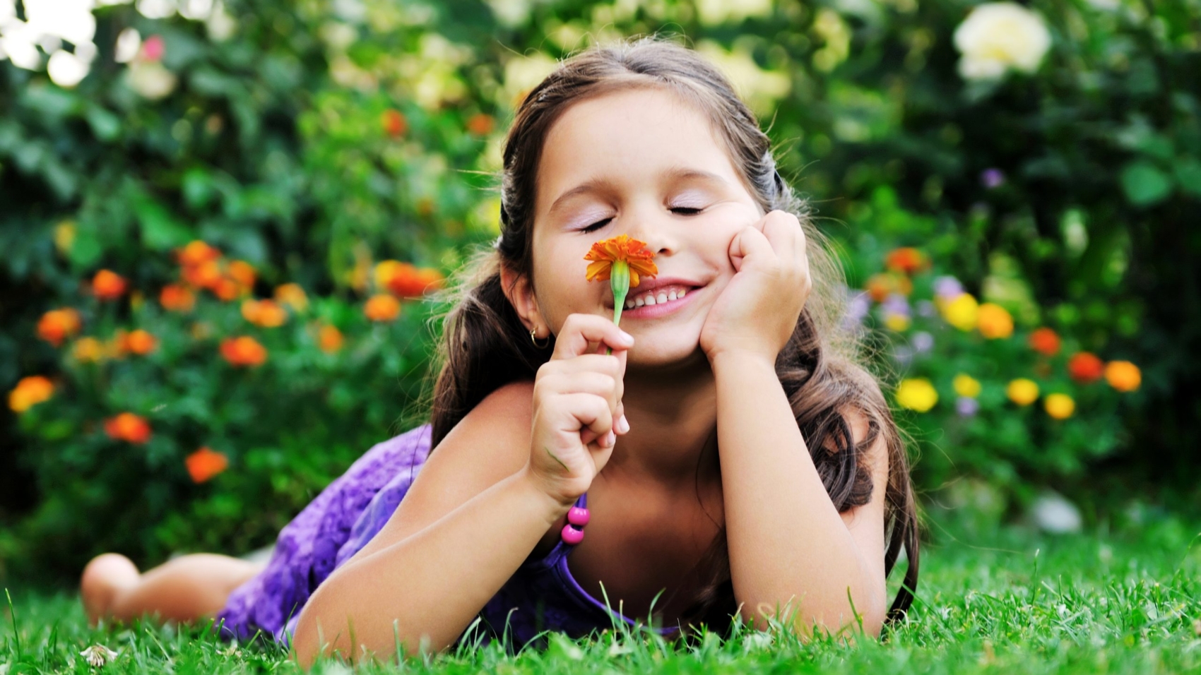 happy young girl children relax lie and have fun on grass with flower